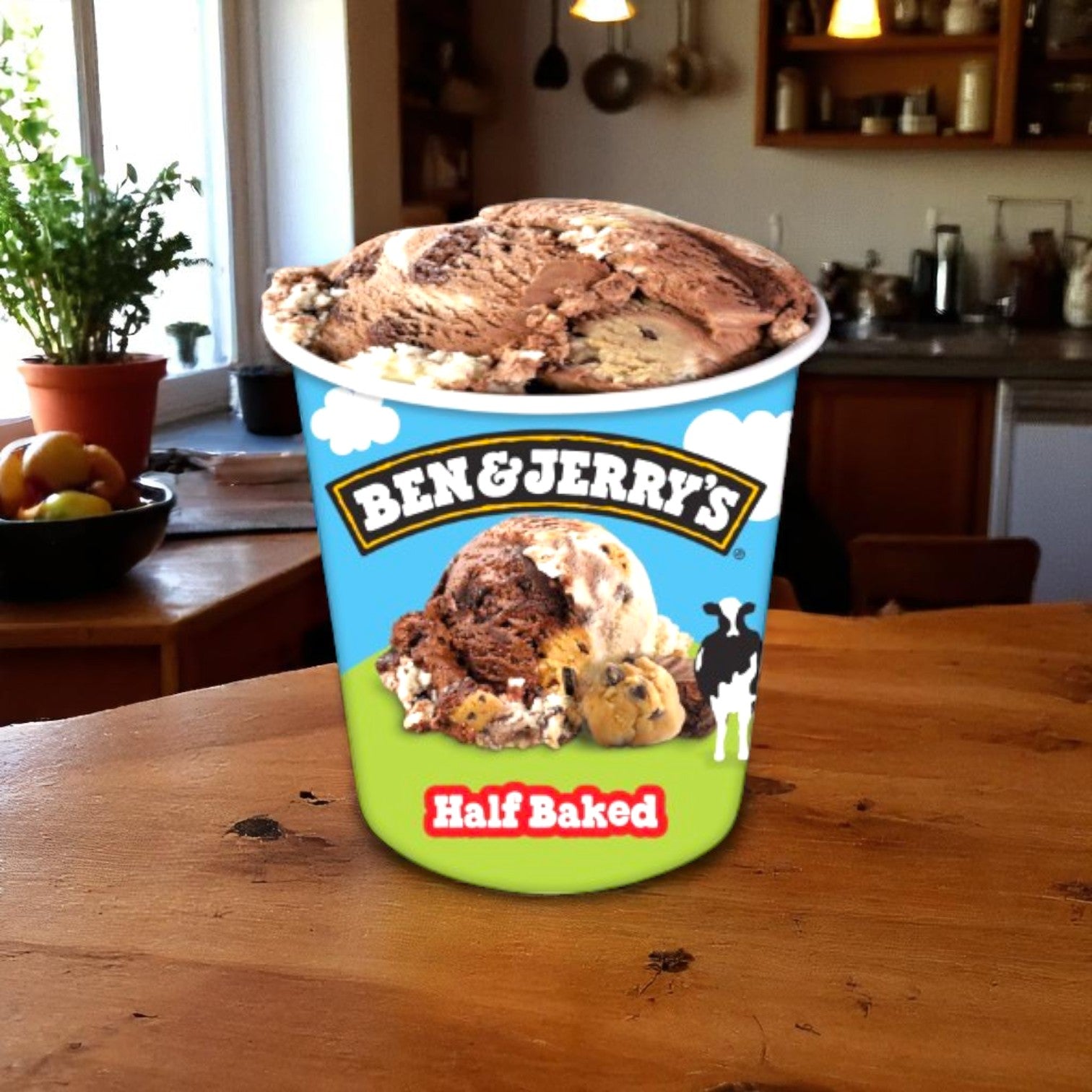 An Easy Lunches Ben & Jerry's Half Baked® Chocolate & Vanilla Ice Cream Pint (16 FL Oz) sits on a wooden kitchen table, with shelves, plants, and fruit in the background. The pint contains cookie dough and fudge brownie pieces.