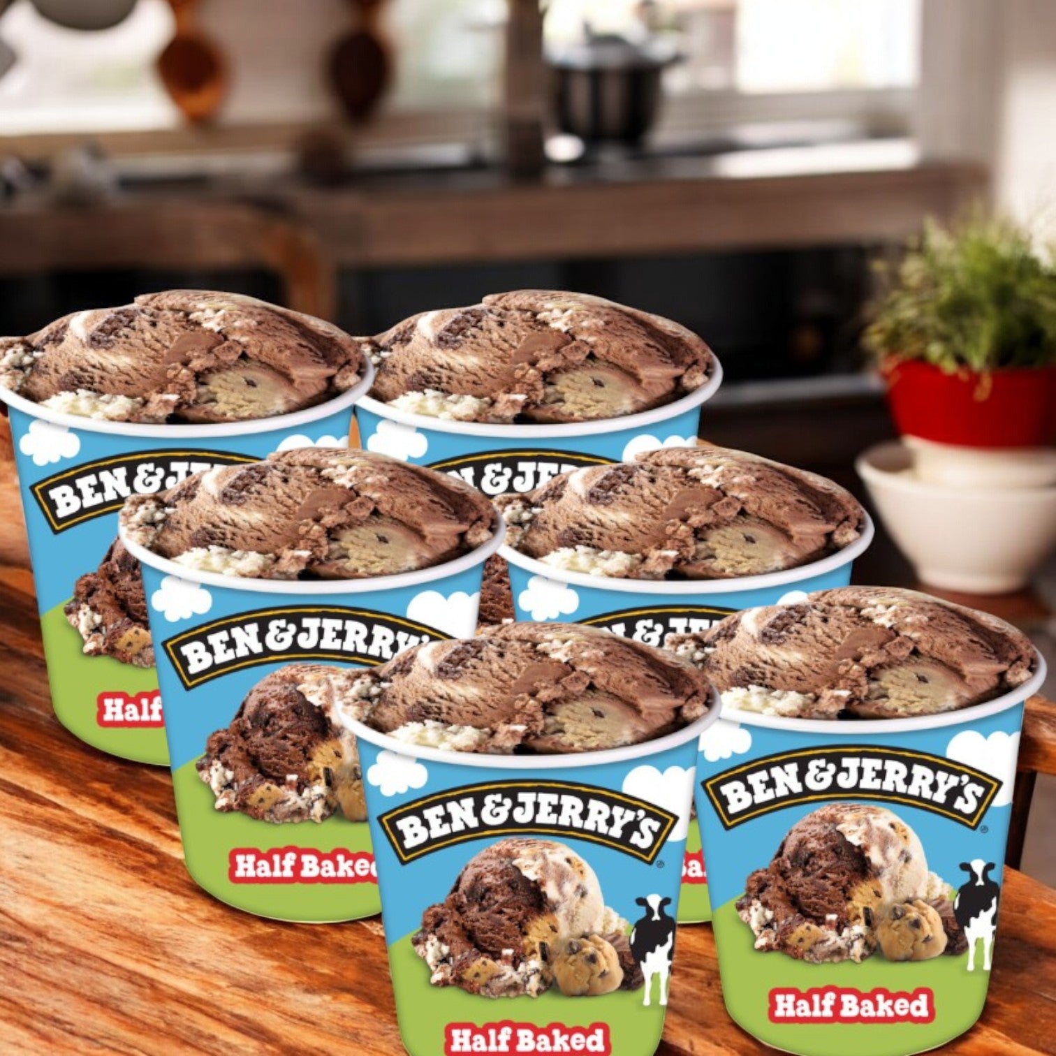 Six pints of Easy Lunches Ben & Jerry’s Half Baked® Chocolate & Vanilla Ice Cream, each 16 FL Oz, featuring cookie dough and brownie pieces, are displayed on a wooden surface with a blurred kitchen in the background.