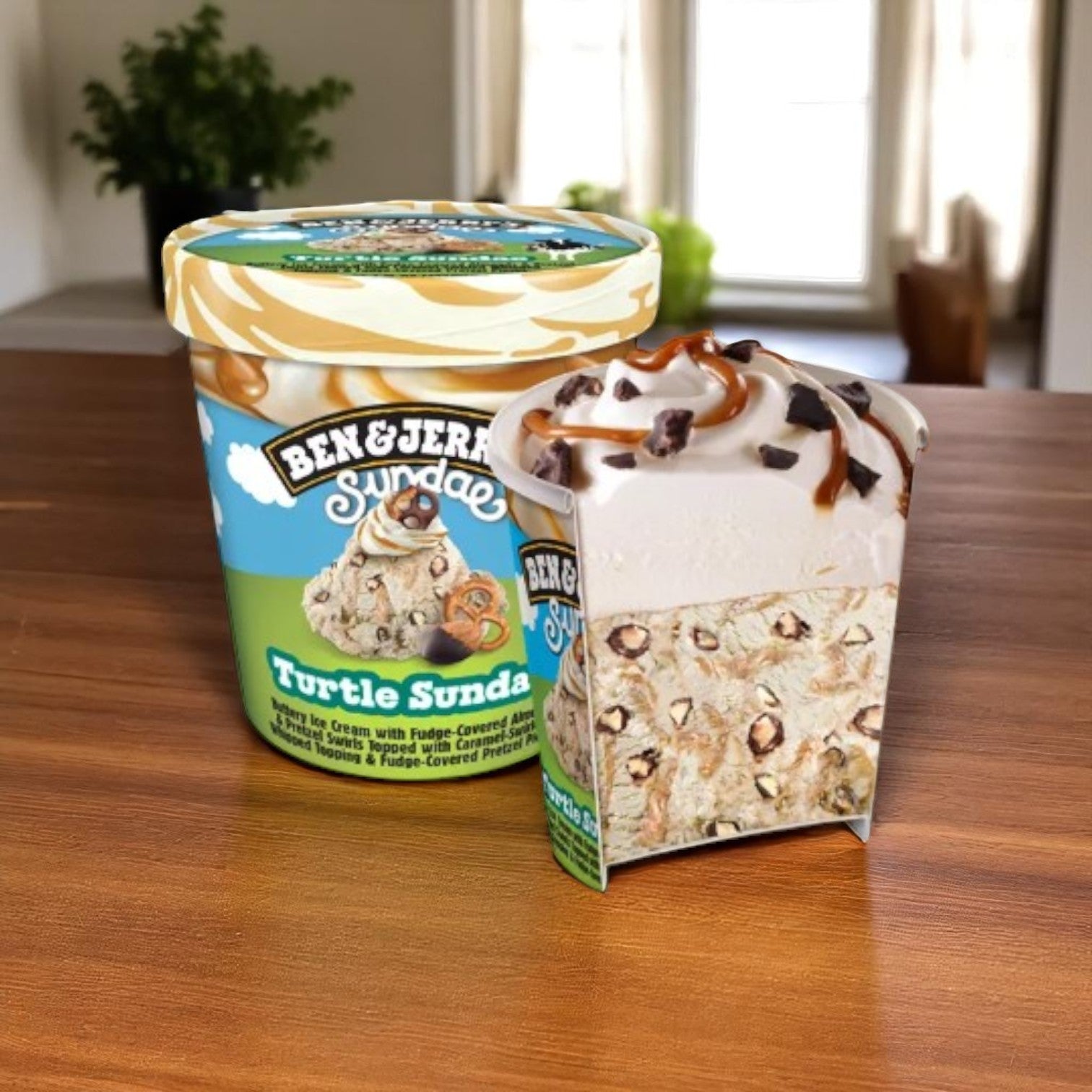 A Ben & Jerry's Turtle Sundae Buttery Ice Cream Pint (14.4 FL Oz) sits on a wooden table, with a cross-section slice showing layers of chocolate chips, caramel swirls, and rich buttery ice cream.