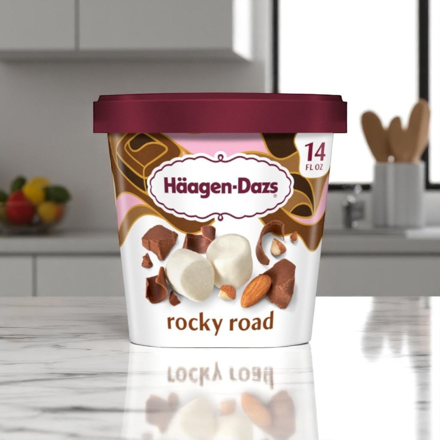 A 14 FL Oz container of Haagen-Dazs Rocky Road Ice Cream from Haagan-Dazs rests on a marble kitchen counter.