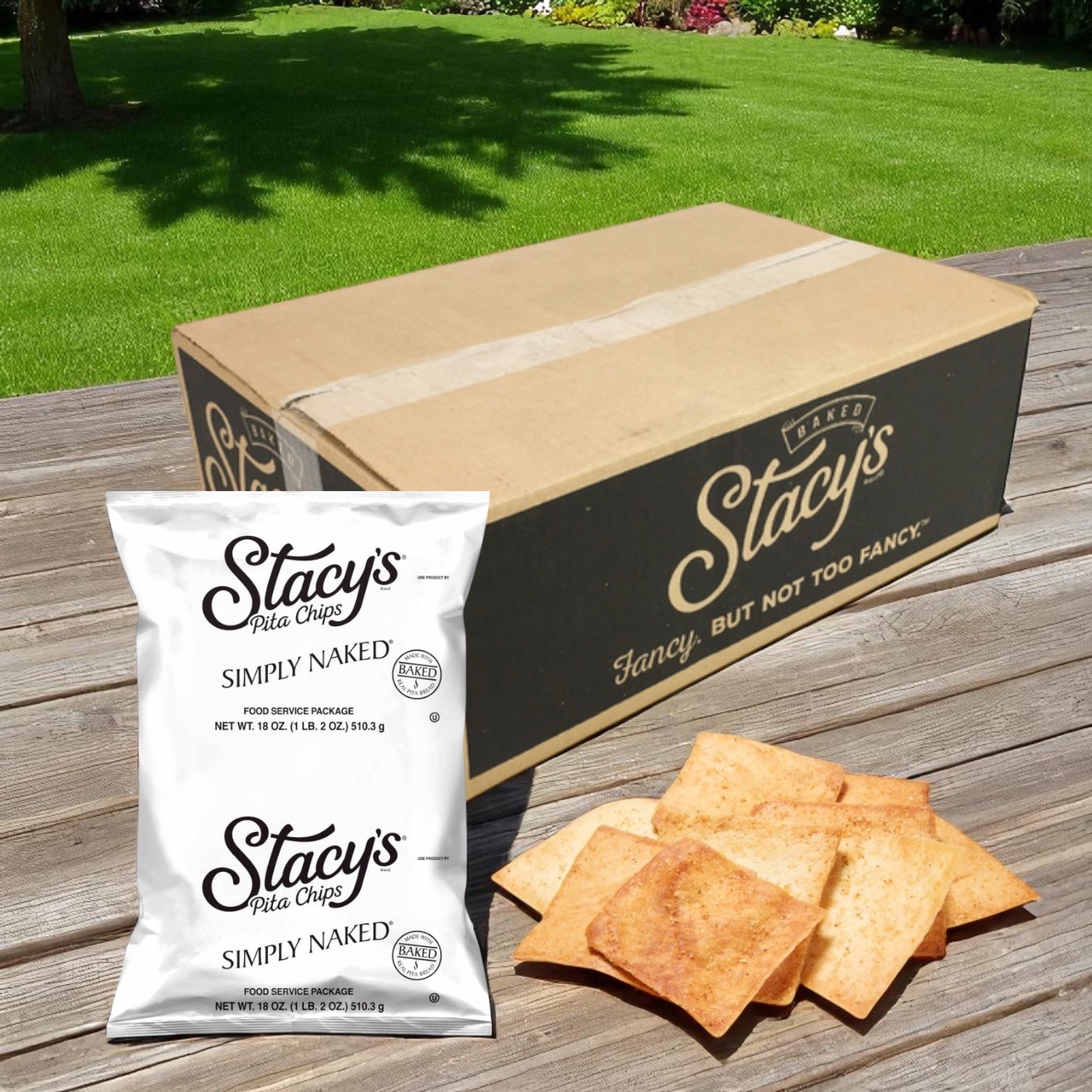 A large box labeled "Easy Lunches" sits on grass with a bag of Stacys Simply Simply Naked Pita Chips 16 oz (6 Count) and several Non-GMO pita chips sprinkled with sea salt displayed in front.