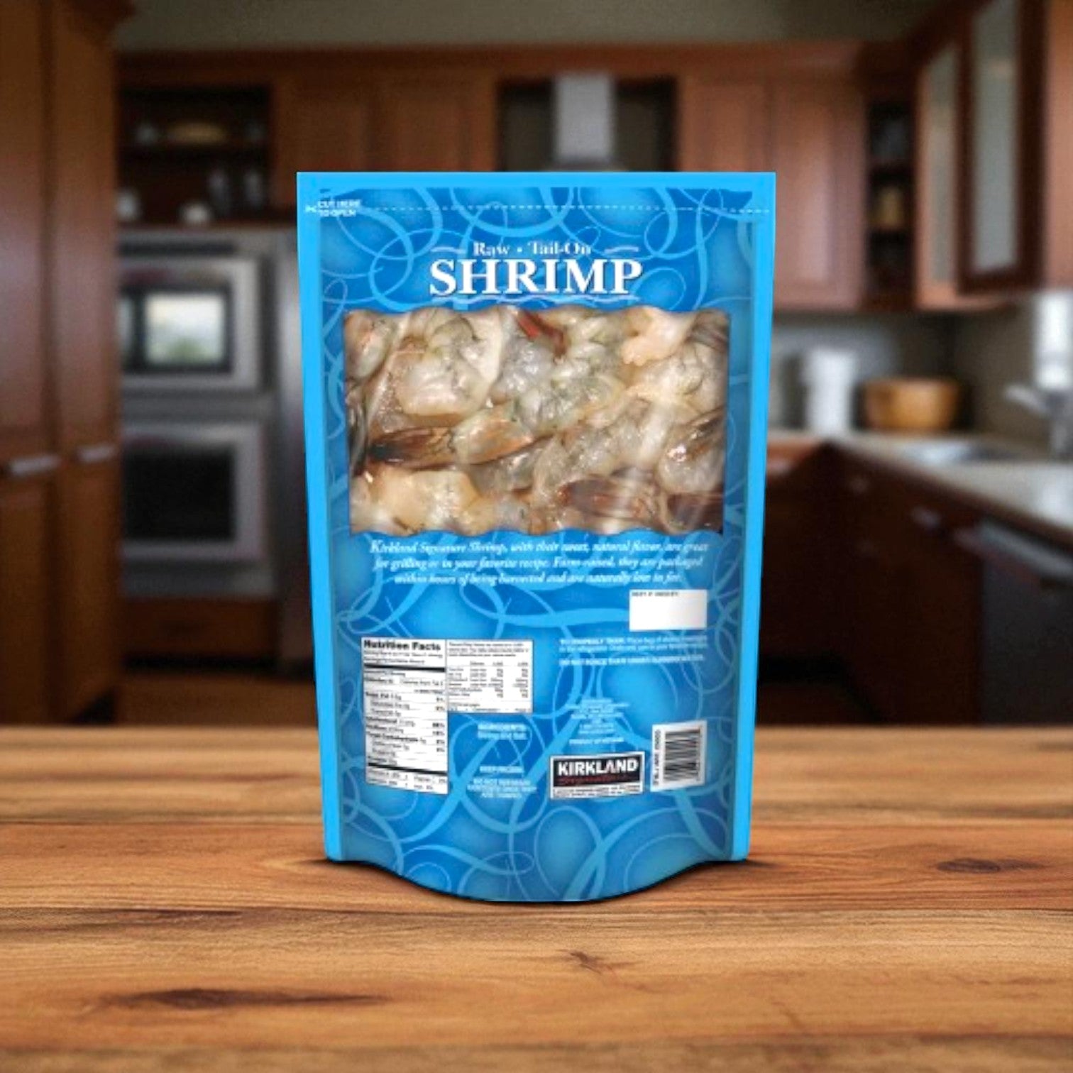 A bag of Easy Lunches Kirkland Signature Raw Tail On Shrimp (1.5 lbs) rests on a wooden kitchen counter with a kitchen in the background.