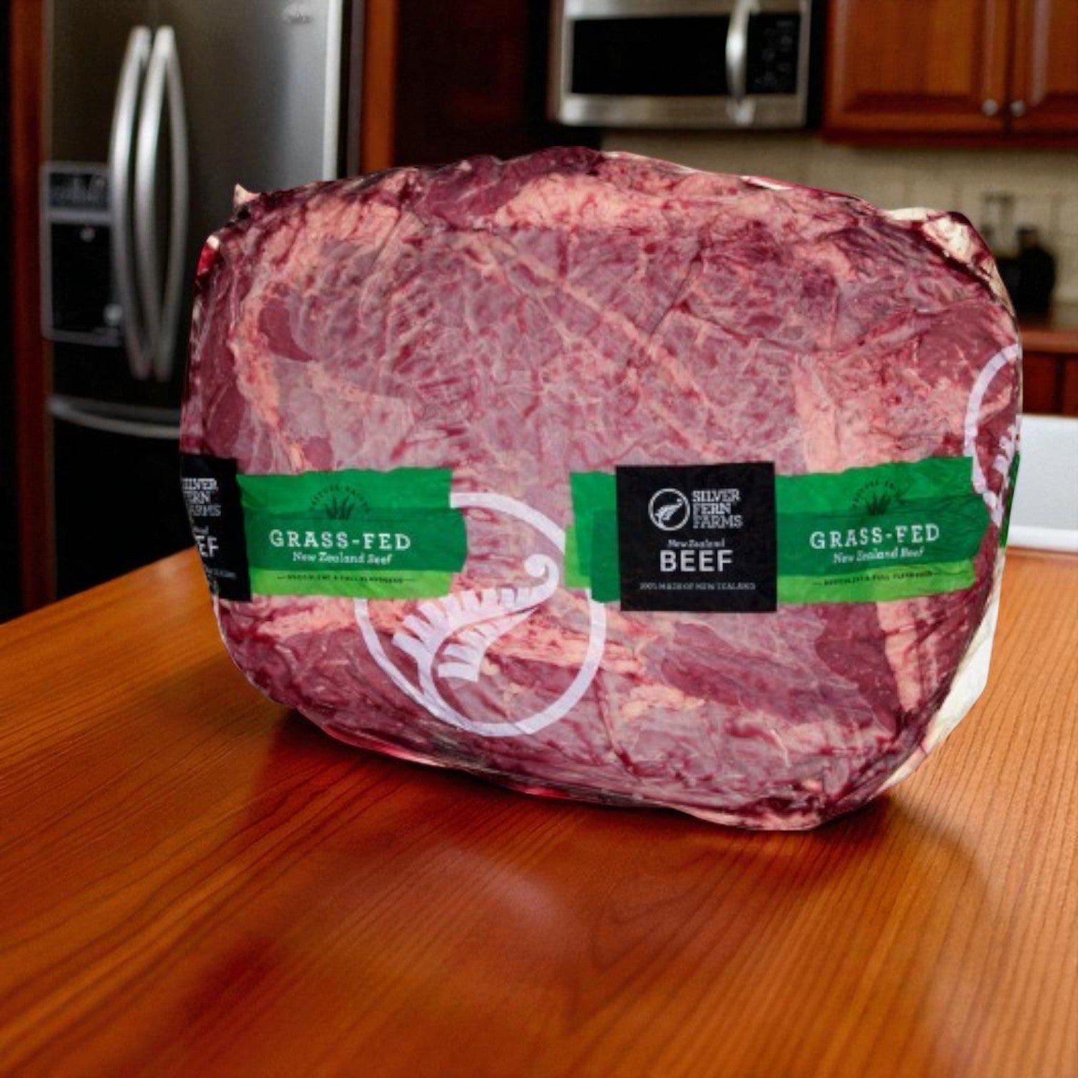 A 14 lb average Halal Beef Chuck Roll by Silver Fern Farms sits vacuum-sealed on a wooden kitchen table.