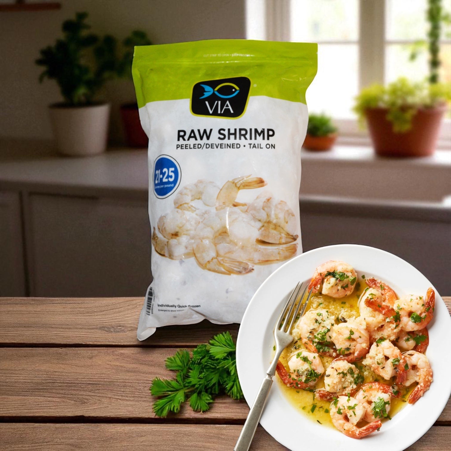 A bag of Easy Lunches VIA Farm-Raised Raw Shrimp, Tail-On, Peeled, Deveined, 21-25 ct, 2 lbs sits on a wooden table beside a plate of cooked shrimp garnished with herbs and parsley.