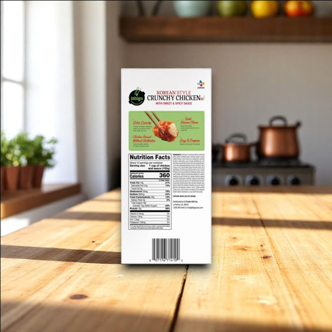 A 3-count, 56 oz bag of Easy Lunches Bibigo Korean Style Crunchy Chicken with Sweet & Spicy Sauce sits on a wooden kitchen table, displaying nutrition facts on the back, with a stove and kitchen items visible in the background.
