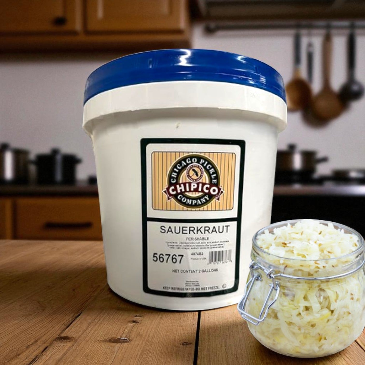 A large white Vienna Beef container labeled "Vienna Chipico Fresh Sauerkraut (2 Gallon)" sits on a kitchen counter beside a small jar of sauerkraut, with utensils in the background—perfect naturally fermented cabbage for foodservice.