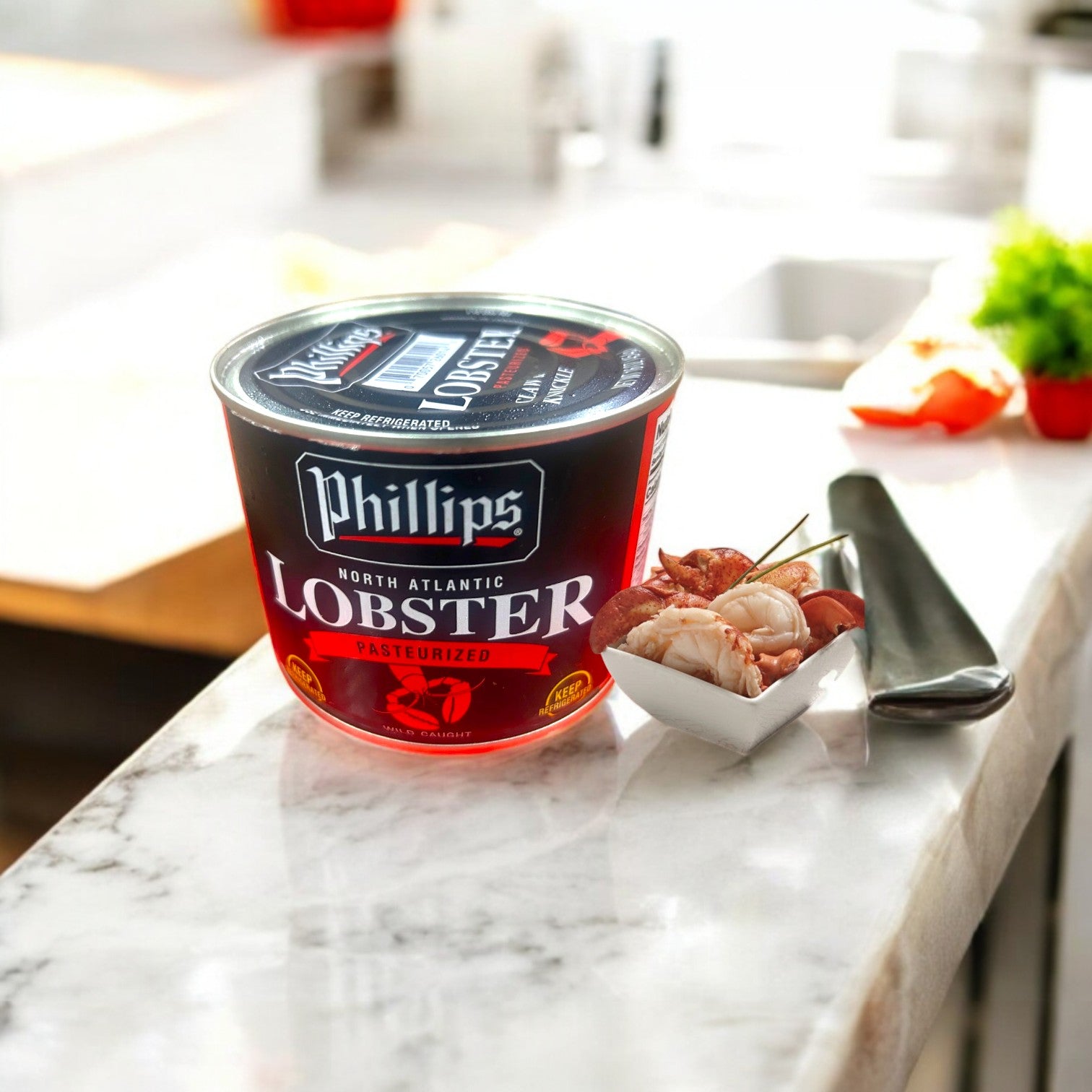 A 16-ounce container of Phillips Foods Lobster Meat sits on a marble counter beside a small dish of ready-to-use premium lobster meat and a fork.