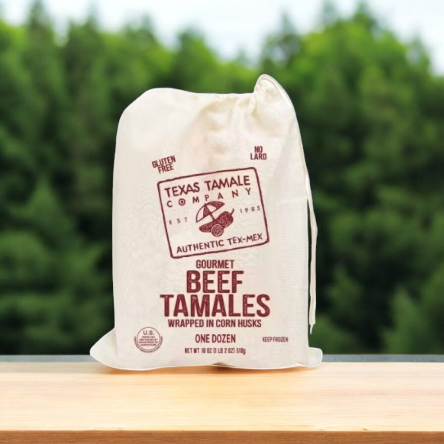 An 18 oz bag of Texas Tamale Company Beef Tamales, delivering rich Tex-Mex flavor with a gluten-free and no-lard label, set against a blurred green backdrop.