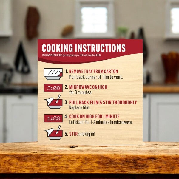 A printed card detailing cooking instructions for Smart Ones Ziti Marinara: remove tray, microwave for 3 minutes, stir, microwave for 1 minute, and stir again. The card is placed on a kitchen counter.