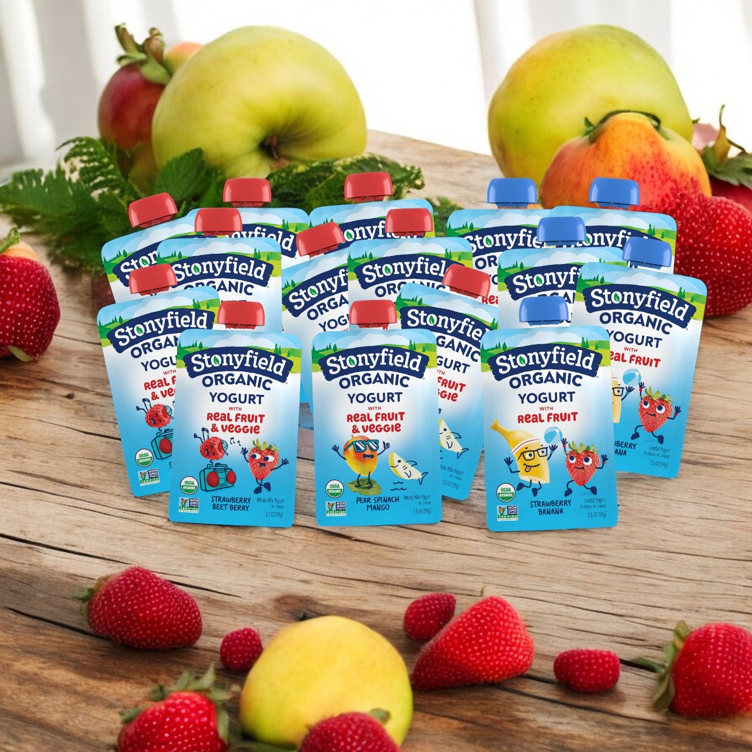 A Stonyfield's 15 Bundle Pack, which includes three delightful yogurt flavors (five of each), is displayed on a wooden surface surrounded by fresh strawberries, apples, and bananas.