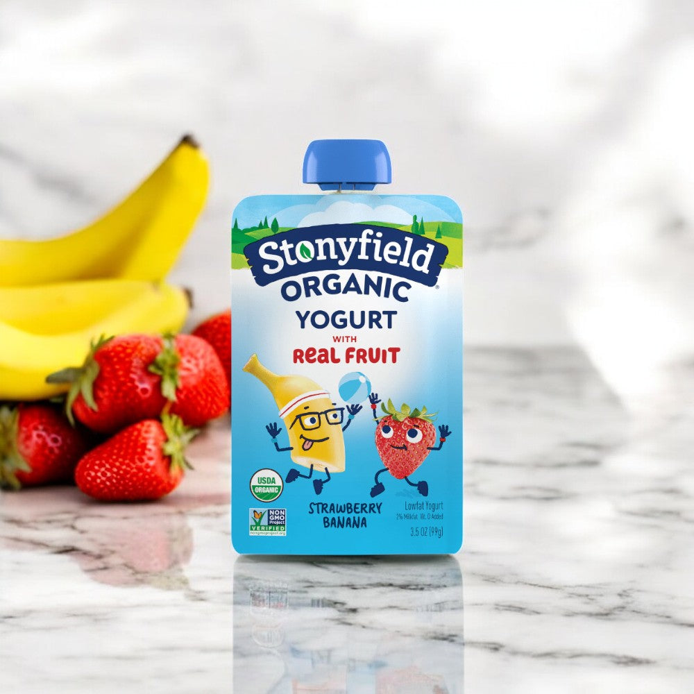 A pouch of Stonyfield's Stonyfield Yogurt Strawberry Banana Pouch is placed on a marble surface with fresh strawberries and bananas in the background, making it an ideal protein snack.