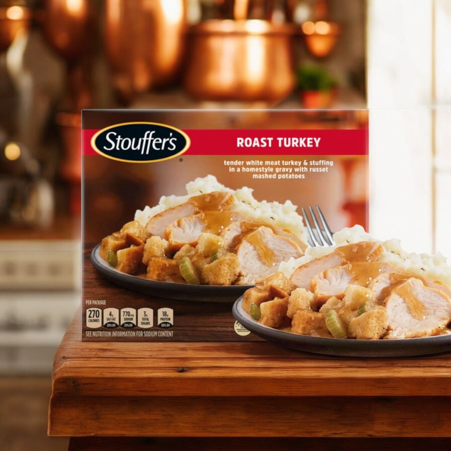 A Stouffer's Roast Turkey frozen meal, featuring turkey, stuffing, mashed potatoes, and gravy, sits on a wooden counter with a kitchen background. This convenient meal option is part of the Stouffer's Bundle! which includes 3 Stouffer's Classics Spaghetti With Meat Sauce, 3 Stouffer's Roast Turkey meals, and 3 Stouffer's Classics Fettuccini Alfredo meals—9 delicious options in total for any occasion.