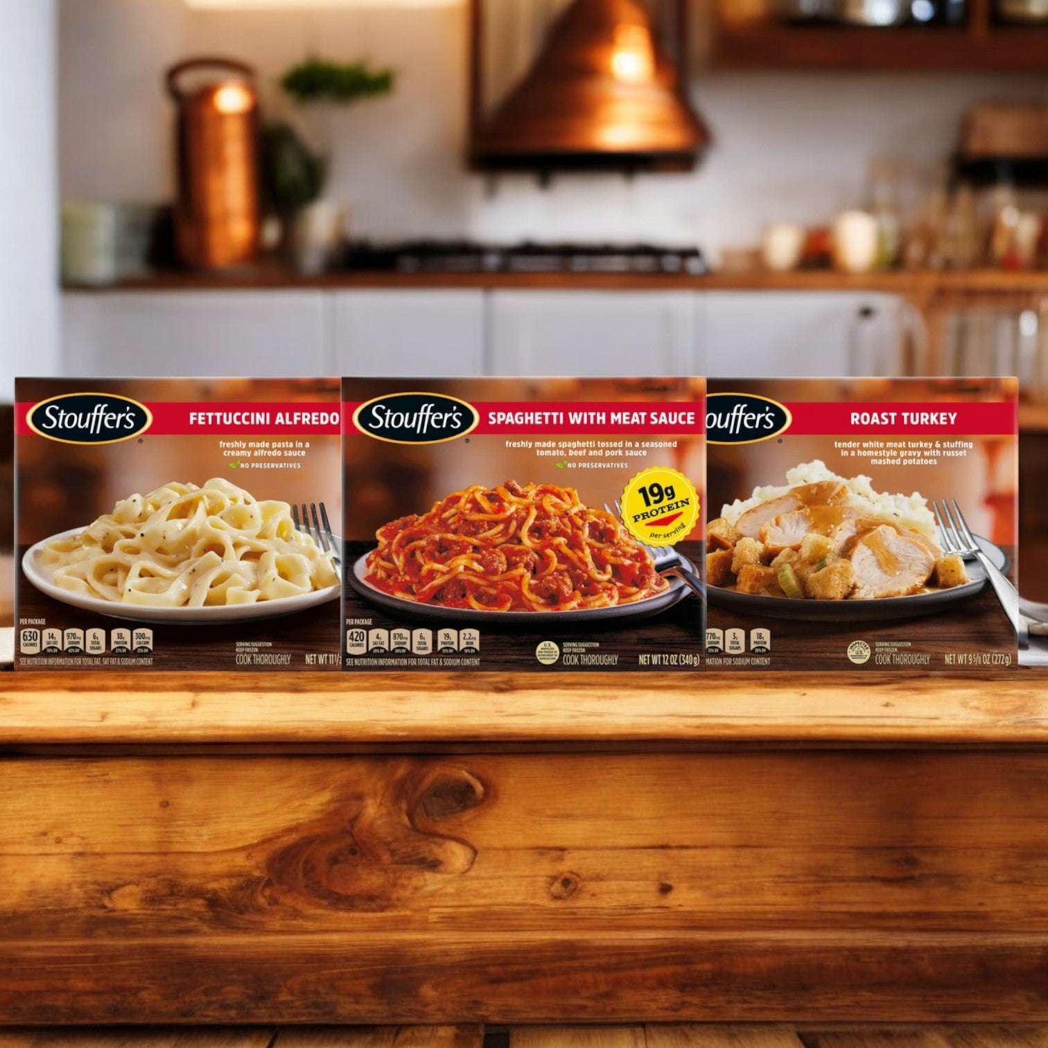 Image of a kitchen counter displaying a Stouffer's Bundle! 1 - Stouffer's Classics Spaghetti With Meat Sauce, 1 - Stouffer's Roast Turkey, and 1 - Stouffer's Classics Fettuccini Alfredo. Kitchen appliances and utensils are visible in the background, showcasing this convenient selection of classic comfort meals from the trusted brand, Stouffer's.