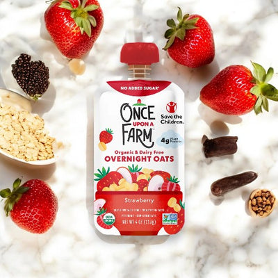 Once Upon a Farm's Strawberry Patch 1-3.2 oz pouch, crafted with organic ingredients, is displayed amidst fresh strawberries, blackberries, oats, and other nutritious choices on a light background.