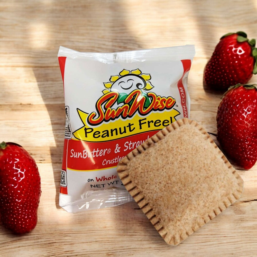 A Sunwise Sunbutter and Strawberry Jelly Sandwich in its packaging, featuring nutritious sunflower seed butter and strawberry jelly, placed on a wooden surface with three strawberries nearby.