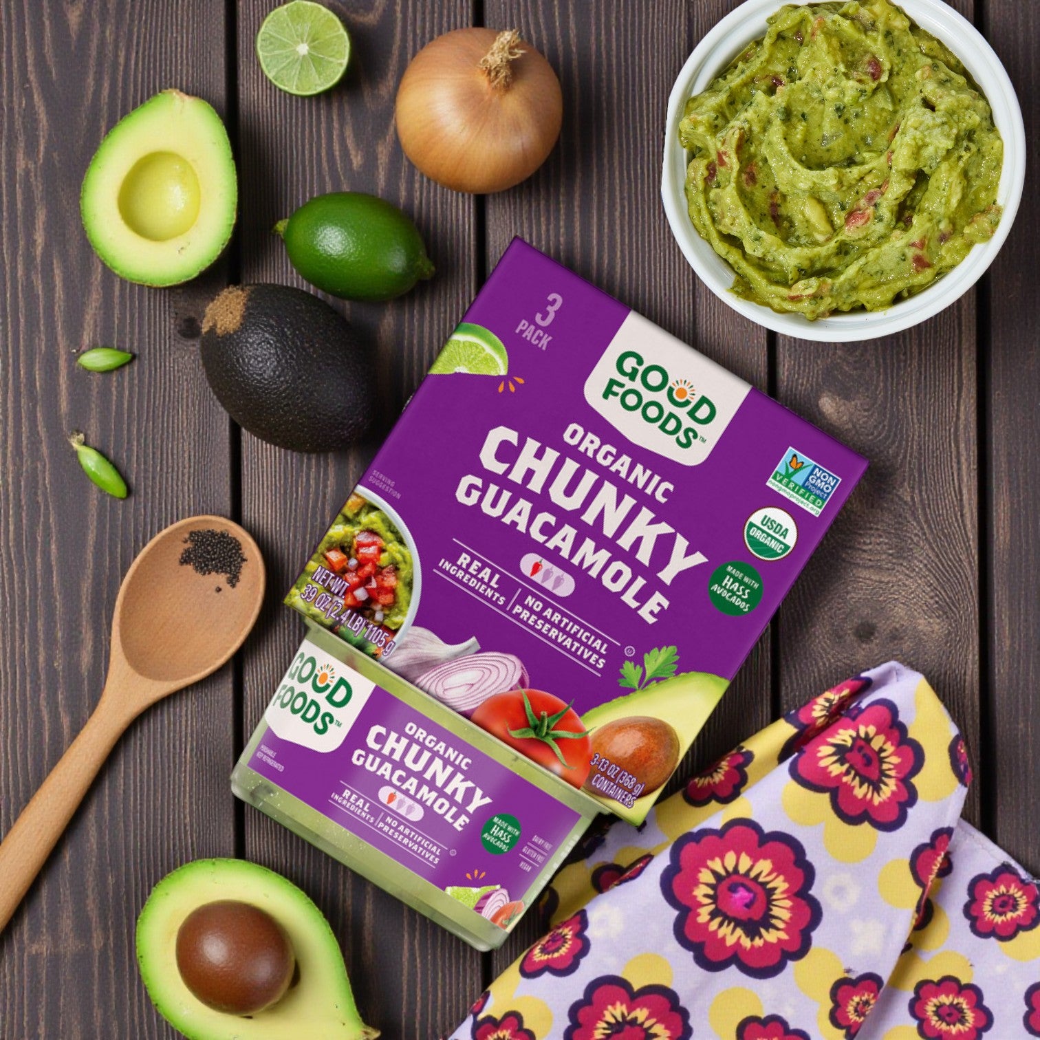 Top view of a table with guacamole ingredients, a bowl of Good Foods Organic Chunky Guacamole, and an avocado next to a Combo Pack: Good Foods Organic Chunky Guacamole + Texas Tamale Company Tamale Fiesta (6 Dozen Total)—the perfect snack pairing!.