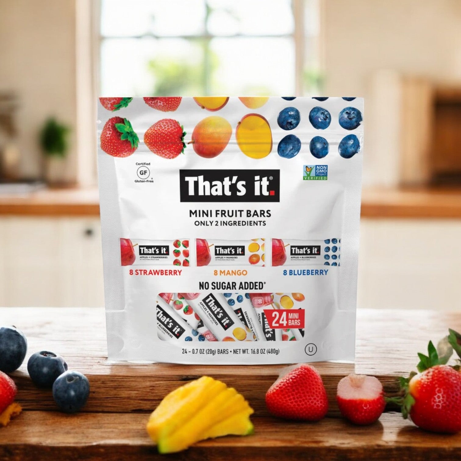 A 24-count pack of That's it Mini Fruit Bars, featuring strawberry, mango, and blueberry flavors, sits on a kitchen counter surrounded by fresh fruits. These bars offer a delicious and nutritious snack.