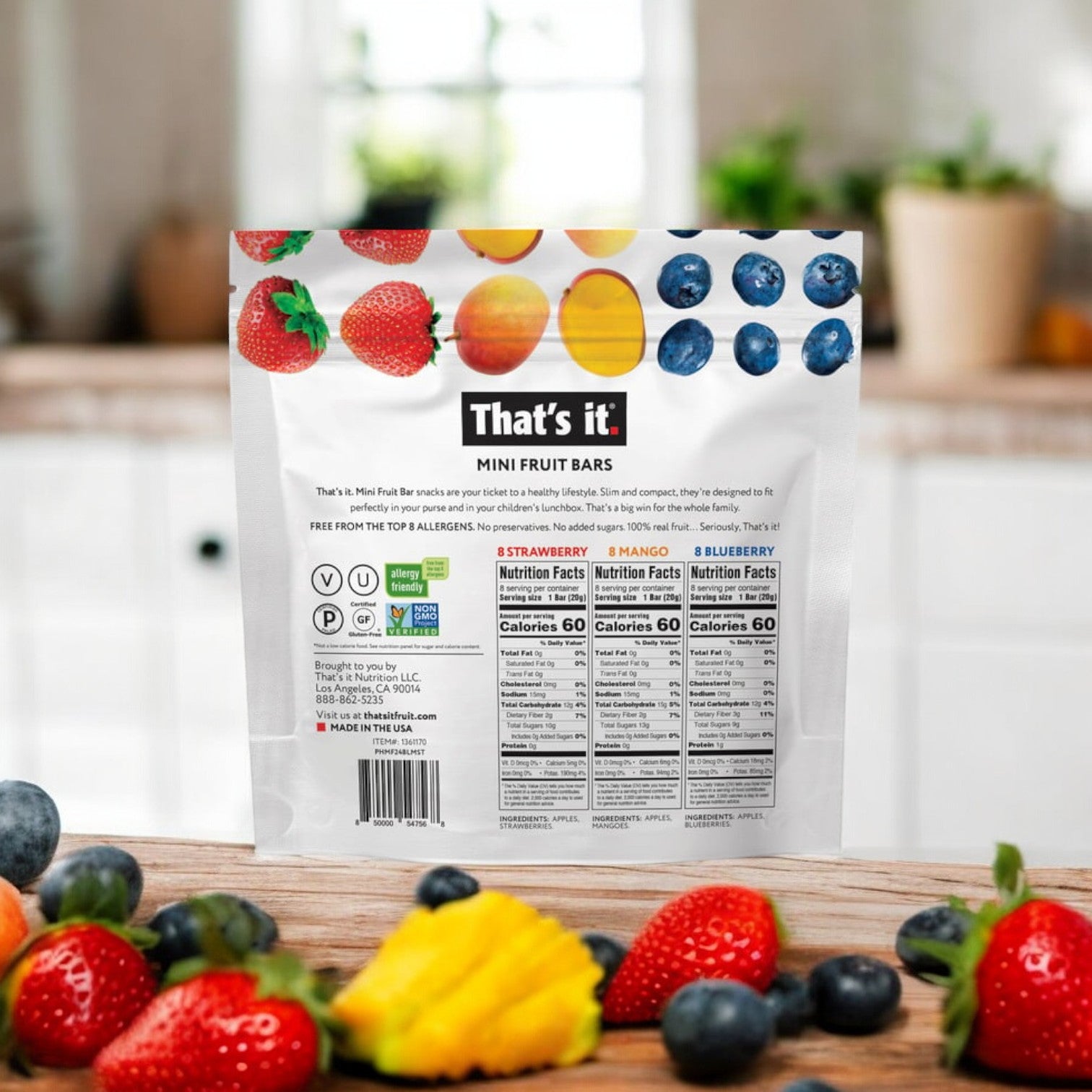 A package of That’s it Mini Fruit Bars, featuring Strawberry, Mango, and Blueberry flavors, rests on a wooden table amid mixed fruits. The packaging highlights multiple certifications and nutritional information, underscoring its value as an ideal wholesome snack.