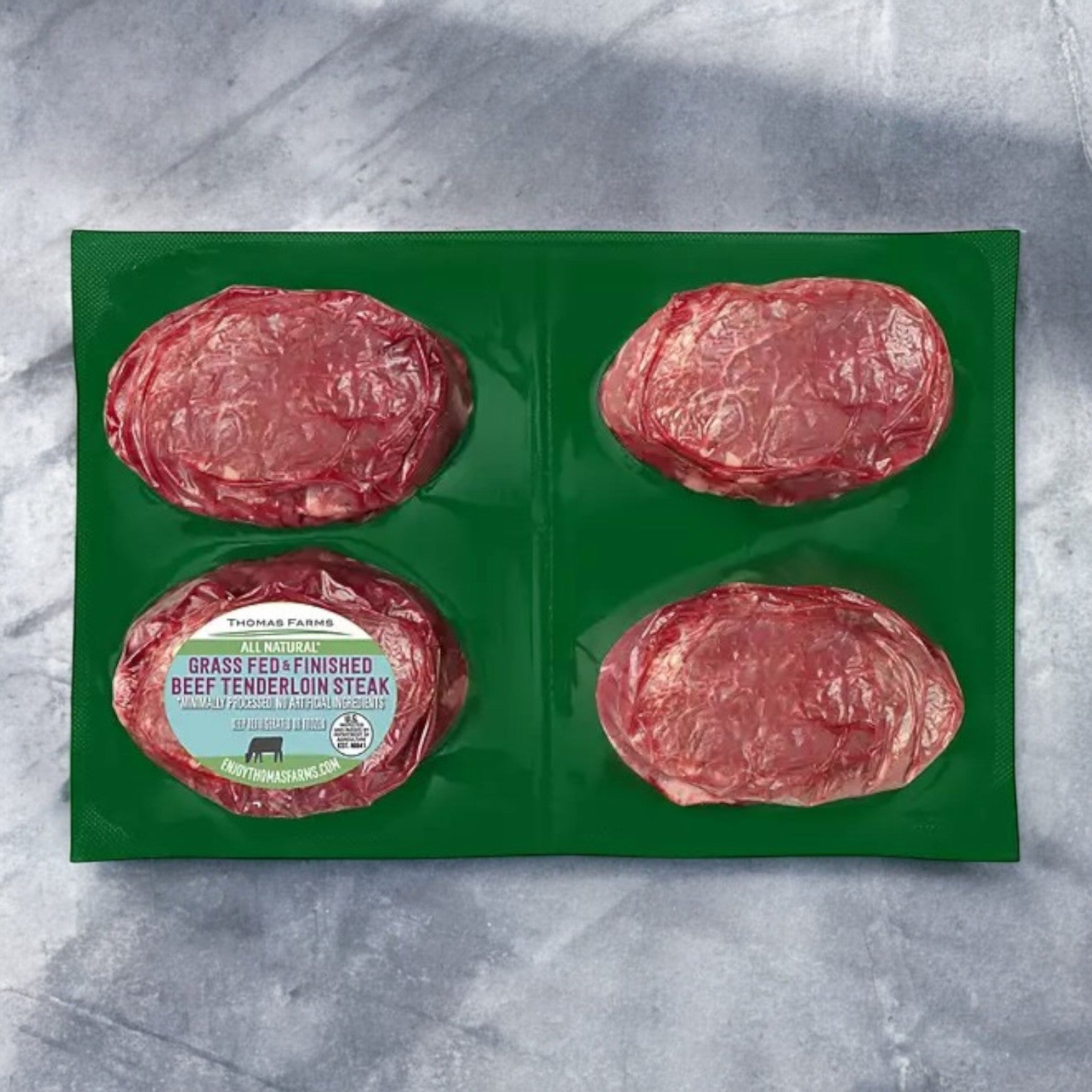 Indulge in a gourmet dining experience with the "Tenderloin Beef Steak- Thomas Farms Grass Fed" pack, which includes four vacuum-sealed steaks. Packaged in green, these tender steaks are perfect for those craving the rich flavor of grass-fed beef.