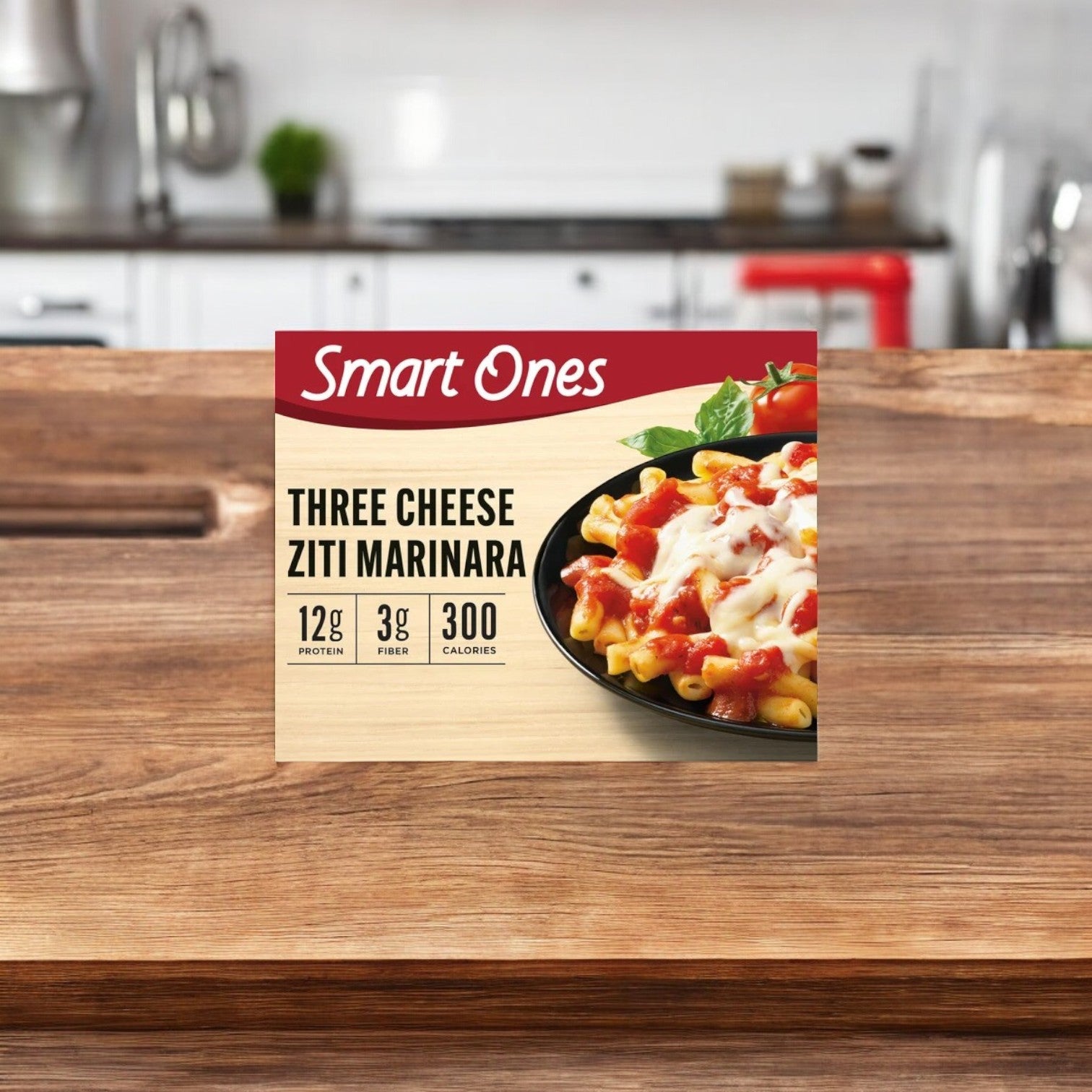 A box of Smart Ones Ziti Marinara, Three Cheese, 9 oz. - 1 Count rests on a wooden kitchen surface, showcasing its nutritional information: 12g protein, 3g fiber, and 300 calories. Perfectly microwaveable for a quick and delicious meal.