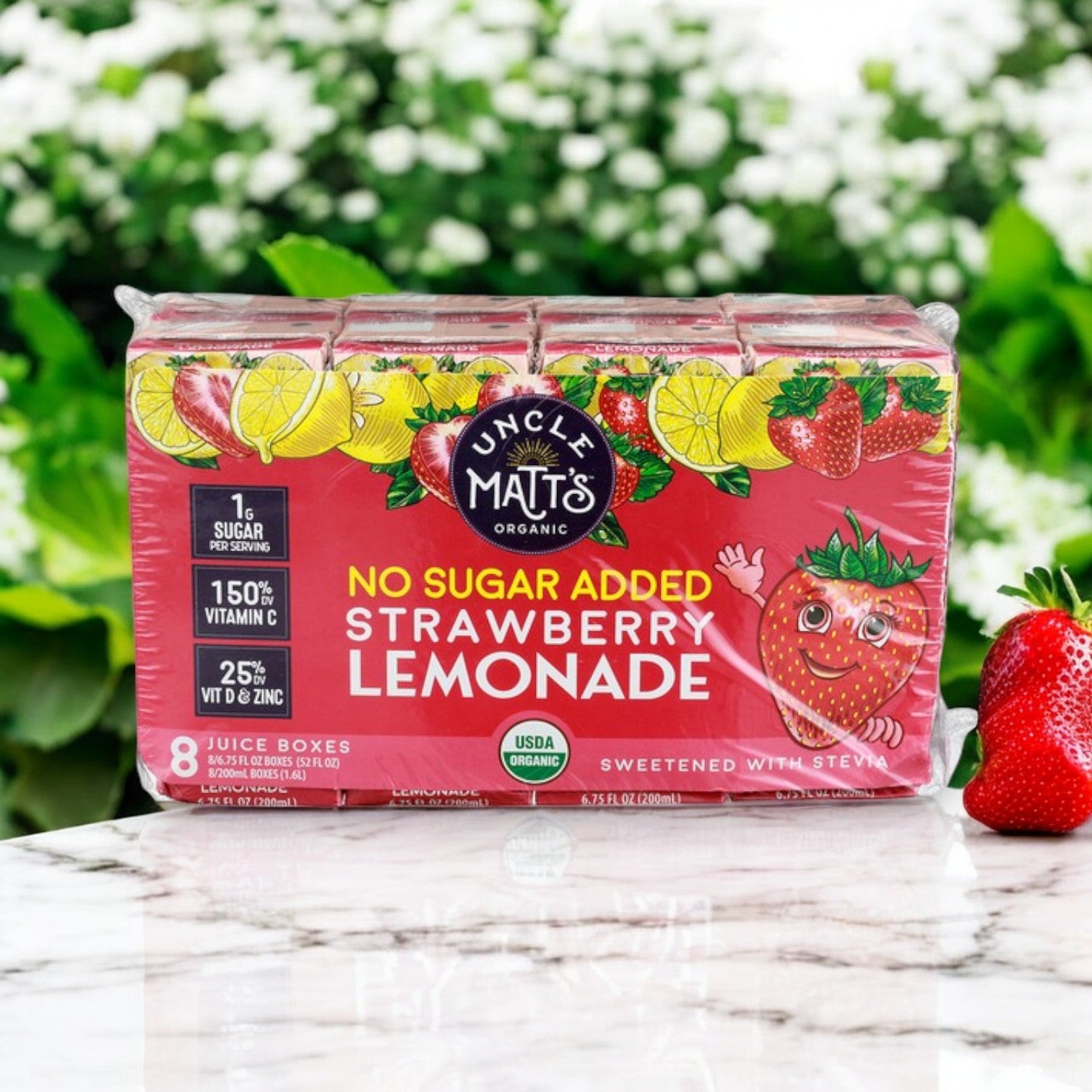 Uncle Matt's Organic No Sugar Added Strawberry Lemonade Juice Boxes, 6.75 fl oz (8-Pack), with Immune Support, are displayed on a marble surface alongside a fresh strawberry.