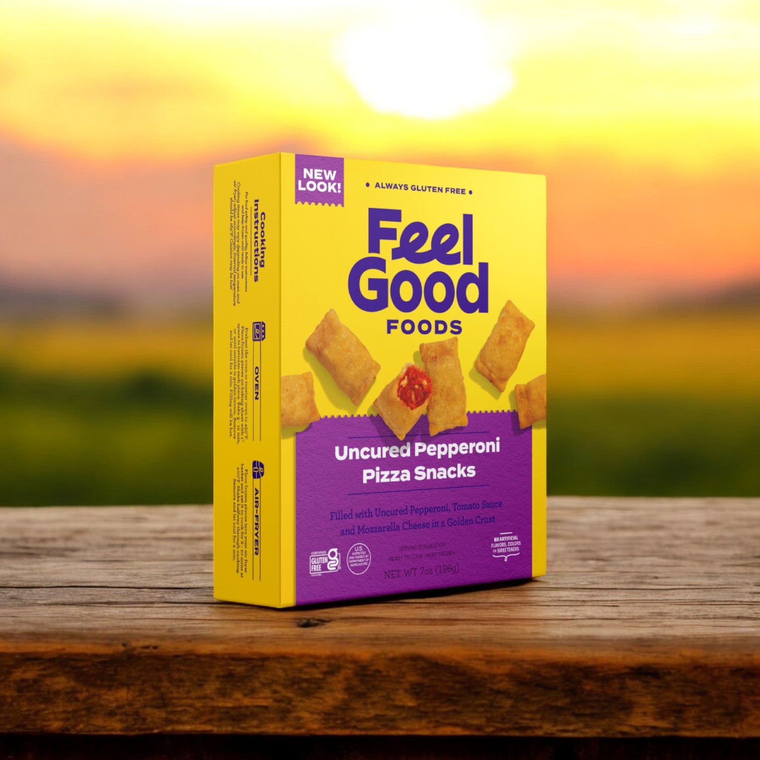 A box of Feel Good Foods Uncured Pepperoni Pizza Snacks, 7 oz. - 1 Count, featuring a gluten-free crust, rests on a wooden surface with a blurred sunset in the background.