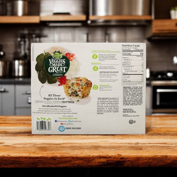 The image shows the back of a box of Veggies Made Great Garden Lites Vegetarian Spinach & Egg White Frittata, 20-count - 1 Pack, displaying nutrition facts and product information. This protein-packed breakfast option features a spinach egg white frittata picture on a kitchen counter, highlighting it as a nutritious, low-calorie meal.