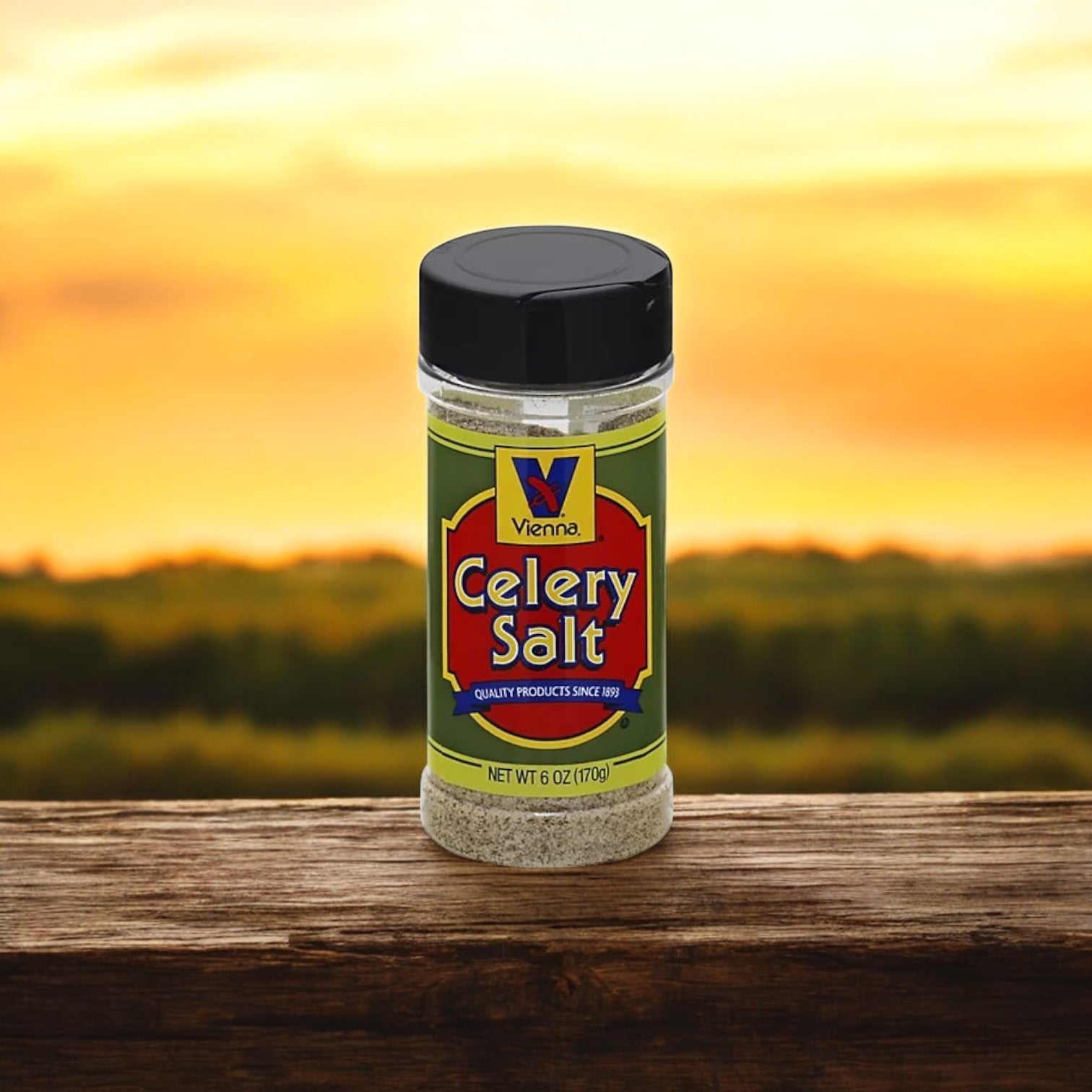 A jar of Vienna Beef's 6 oz. Celery Salt sits on a wooden surface with a blurred outdoor background, making it an ideal seasoning for Chicago-style hot dogs.