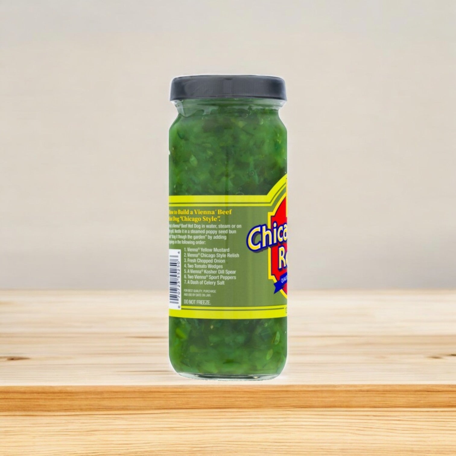 A jar of Vienna Beef's Vienna Relish, Chicago Style 12 oz., with its authentic sweet and tangy Chicago flavor, sits on a wooden surface. Its green label stands vibrant against a plain background.