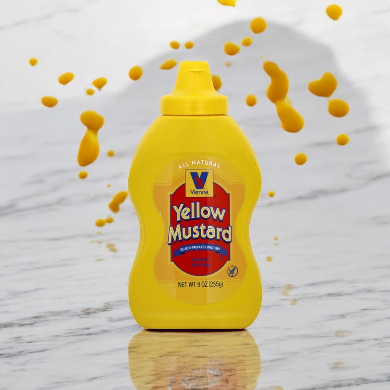 A Vienna Yellow Mustard 9 oz. bottle by Vienna Beef rests on marble, surrounded by artistic mustard droplets, evoking the tangy essence of Chicago-style hot dogs.