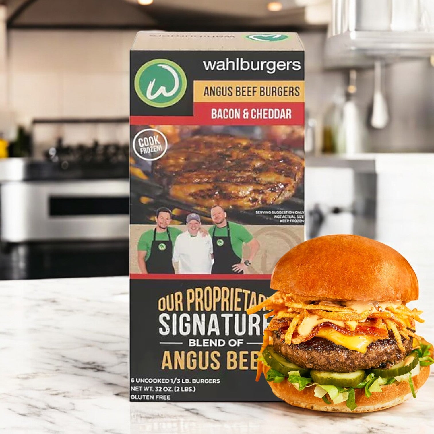 A box of Wahlburgers Frozen Beef Patties, Bacon & Cheddar, 32 oz rests on the kitchen counter, highlighted by a perfectly cooked Angus beef burger with toppings in front.