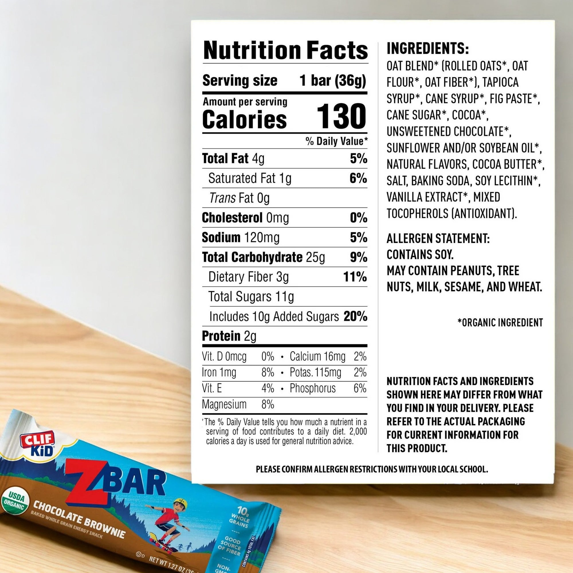 Clif Bar Zbar - Chocolate Brownie Soft Baked Whole Grain Snack Bar (1.27 oz, 1 Count), placed on a wooden table, with detailed nutrition facts and ingredients listed on a white background. These nutritious snack bars are made with whole grains for a wholesome treat kids will love.