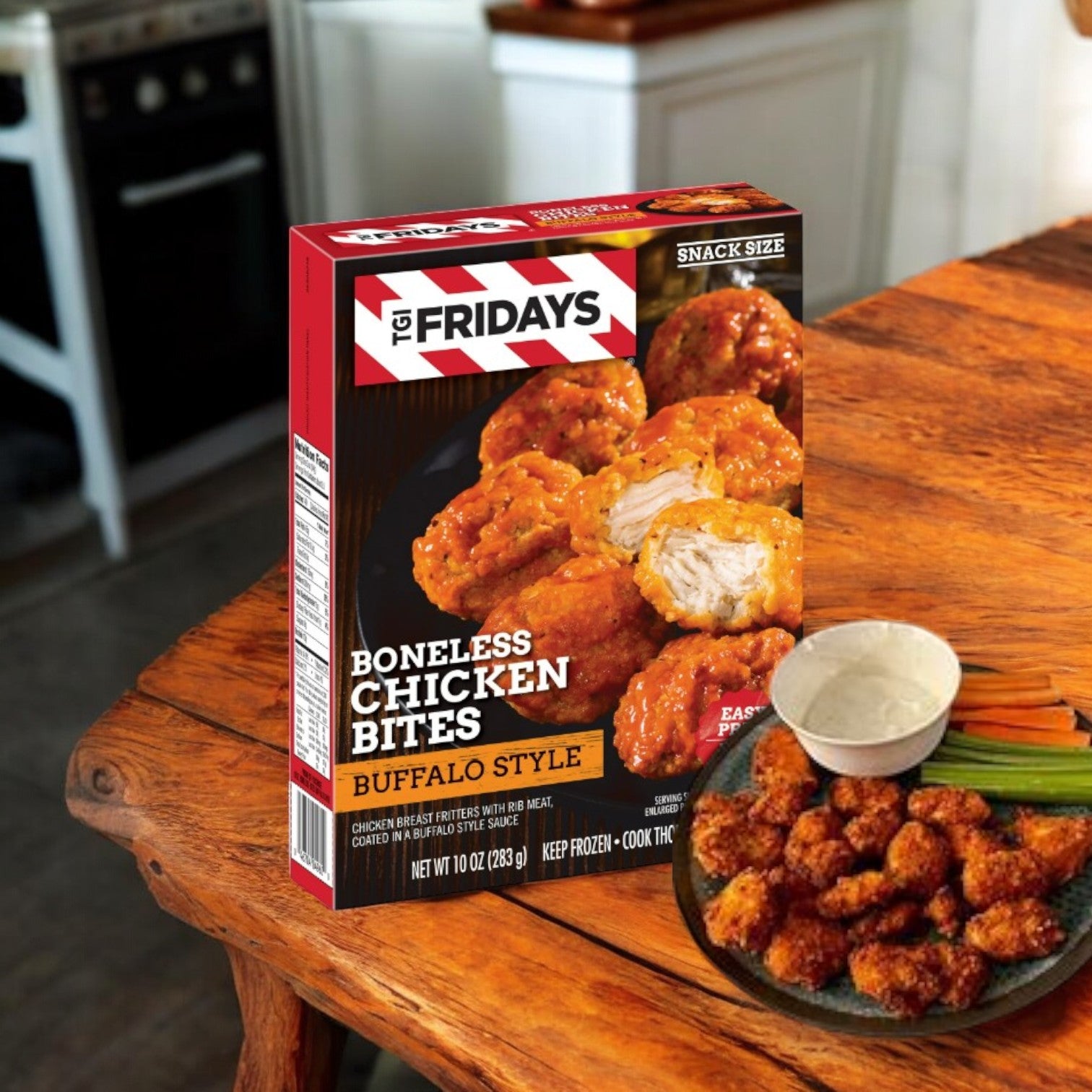 A box of TGI Fridays Frozen Appetizers Buffalo Style Boneless Chicken Bites, 10 oz, is on a wooden table next to a plate of these appetizers and fresh vegetables in a cozy kitchen.