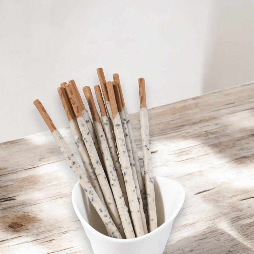 A white bowl contains several Pocky Biscuit Sticks Covered in Cookies & Cream by the brand Pocky, displayed on a wooden surface.