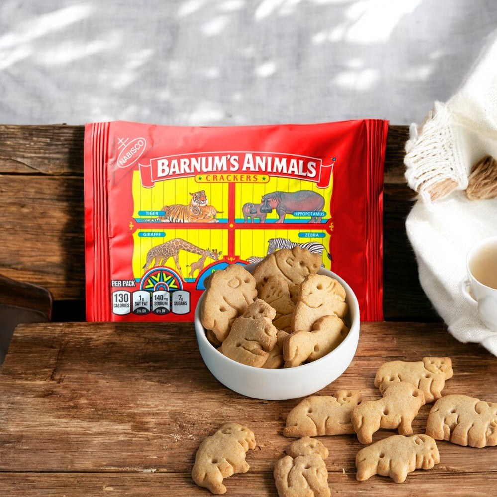 A bag of Barnum's Original Animal Crackers 1 oz- 1 Count, those beloved calcium snacks from Barnum's, is placed on a rustic wooden surface with a small white bowl filled with animal-shaped crackers beside it.