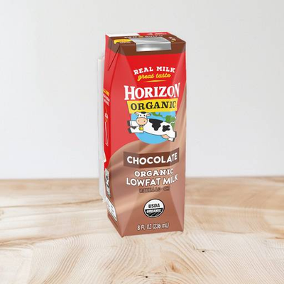 A carton of Horizon Organic Chocolate Milk (8 fl oz) from the brand Horizon is placed on a wooden surface. The white and brown carton, highlighted by its rich text and images, is also fortified with DHA Omega-3 for an added nutritional boost.