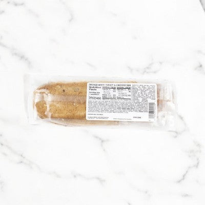 E.A. Sween's Smoked Turkey & Cheddar Sub Sandwiches, made with rustic oat topped rolls, are neatly arranged on a white marble surface, each featuring a detailed nutrition label.