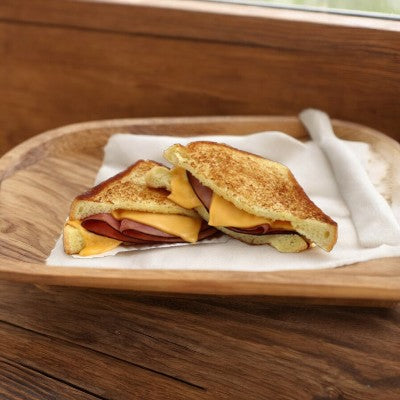 Enjoy a Timber Ridge Grilled Ham & Cheese on Texas Toast, cut in half and elegantly served on a wooden plate with a white napkin.