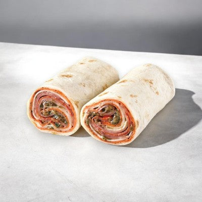 Two halves of a handcrafted sandwich placed on a white surface, showcasing the cross-section with visible layers of meat, vegetables, and sauce tucked inside a flour tortilla. These delectable Italian Style Wraps are part of our Easy Lunches' Variety Sandwich Pack 9 Items! Set, which also includes 3 - Smoked Turkey & Cheddar Sub Sandwiches and 3 - Ham & Swiss On Rustic Oat-Topped Wheat Bread.