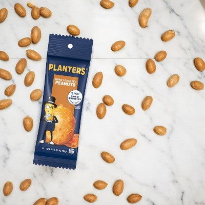 The Planters Honey Roasted Peanuts - 5 bags 1.5 oz each package lies on a marble surface, surrounded by scattered Planters Peanuts, with Mr. Peanut's iconic figure gracing the label.