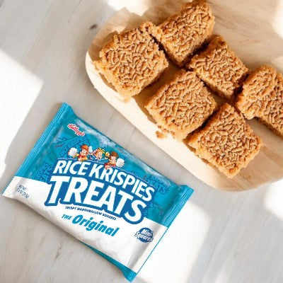 A package of Kellogg's Rice Krispies Treats, 0.78 oz - 1 Count, lies on a table next to several homemade squares of the classic treat on a wooden tray.