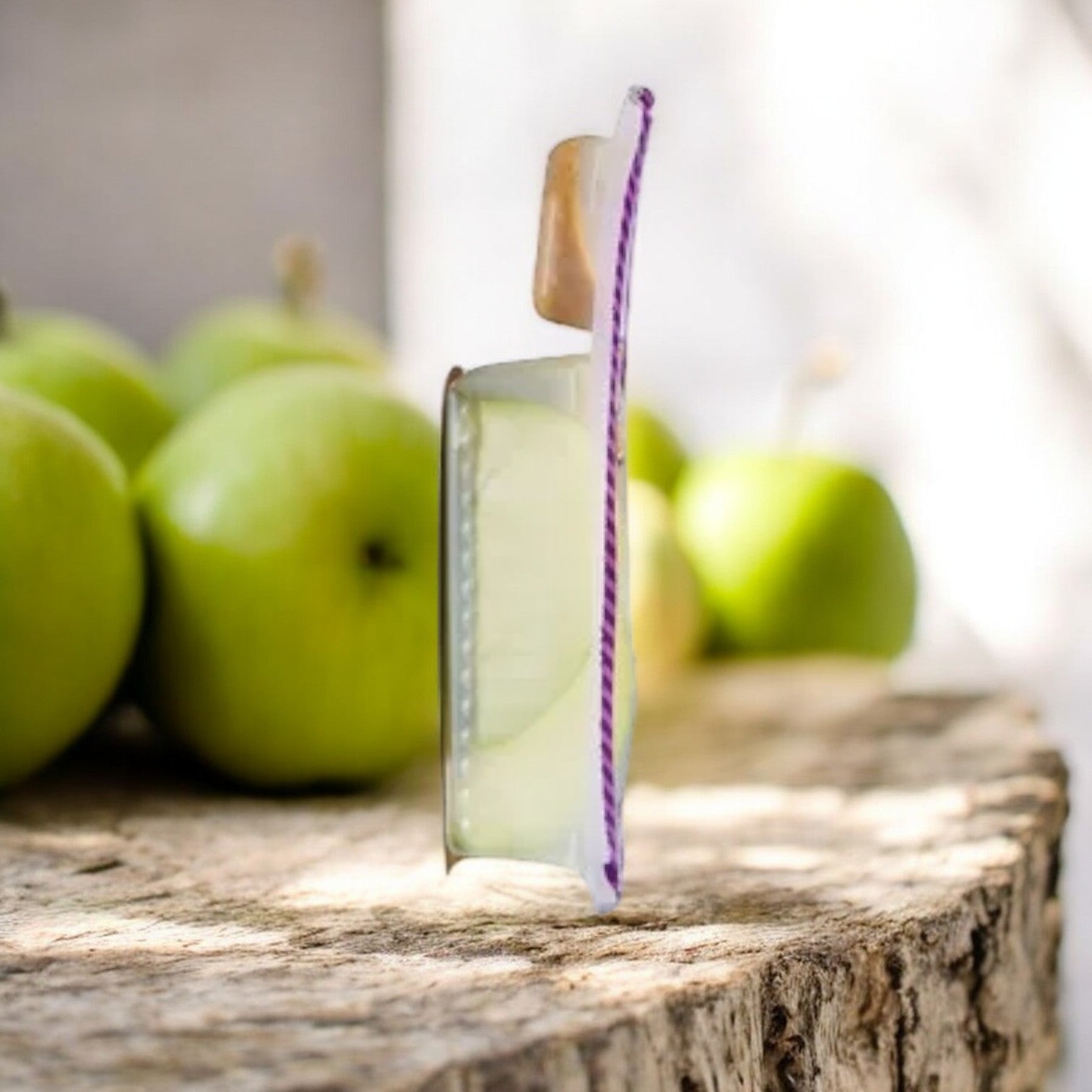 A Dippin' Stix Sliced Apples & Peanut Butter pack sits open on a wooden surface with sliced apples and peanut butter in the background, ready for a nutritious snack.