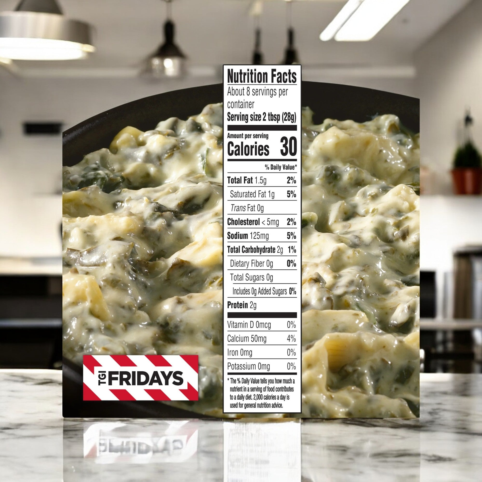 Close-up of TGIF Fridays Spinach & Artichoke Cheese Dip package showing nutrition facts, including serving size and calories. The blurred kitchen background highlights the focus on this frozen snack's irresistible appeal.