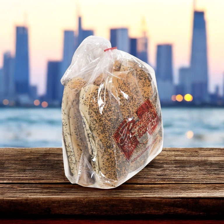 A package of poppy seed bagels sits on a wooden surface, reminiscent of an ideal Vienna Beef hot dog bun from the Chicago-style Hot Dog Kit, with a blurred city skyline in the background.