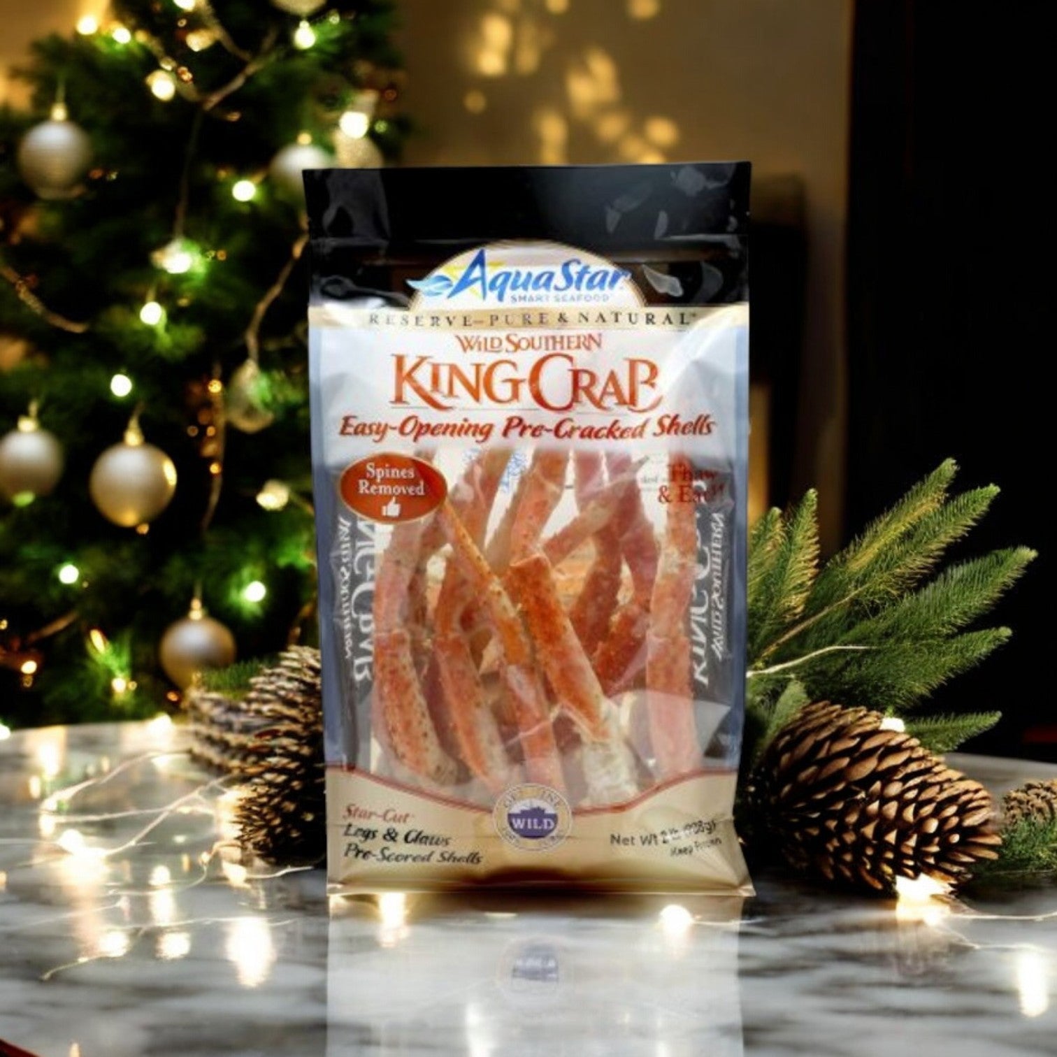 A bag of Aqua Star King Crabs & Cheddar Bay Biscuits Combo from Easy Lunches sits on a marble counter, ready to be part of a festive Seafood Feast. In the background, a decorated Christmas tree and pine branches add holiday charm to the scene.