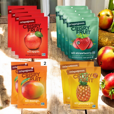 An assortment of Easy Lunches' Crispy Fruit Variety Bundle, including 4 Crispy All Apple, 4 Crispy All Strawberry, 2 Crispy All Mango, and 2 Crispy Pineapple bags displayed in their respective packaging. Fresh apples and a plant are visible in the background. Enjoy a healthy snack with this delicious mix of freeze-dried fruits from Easy Lunches.