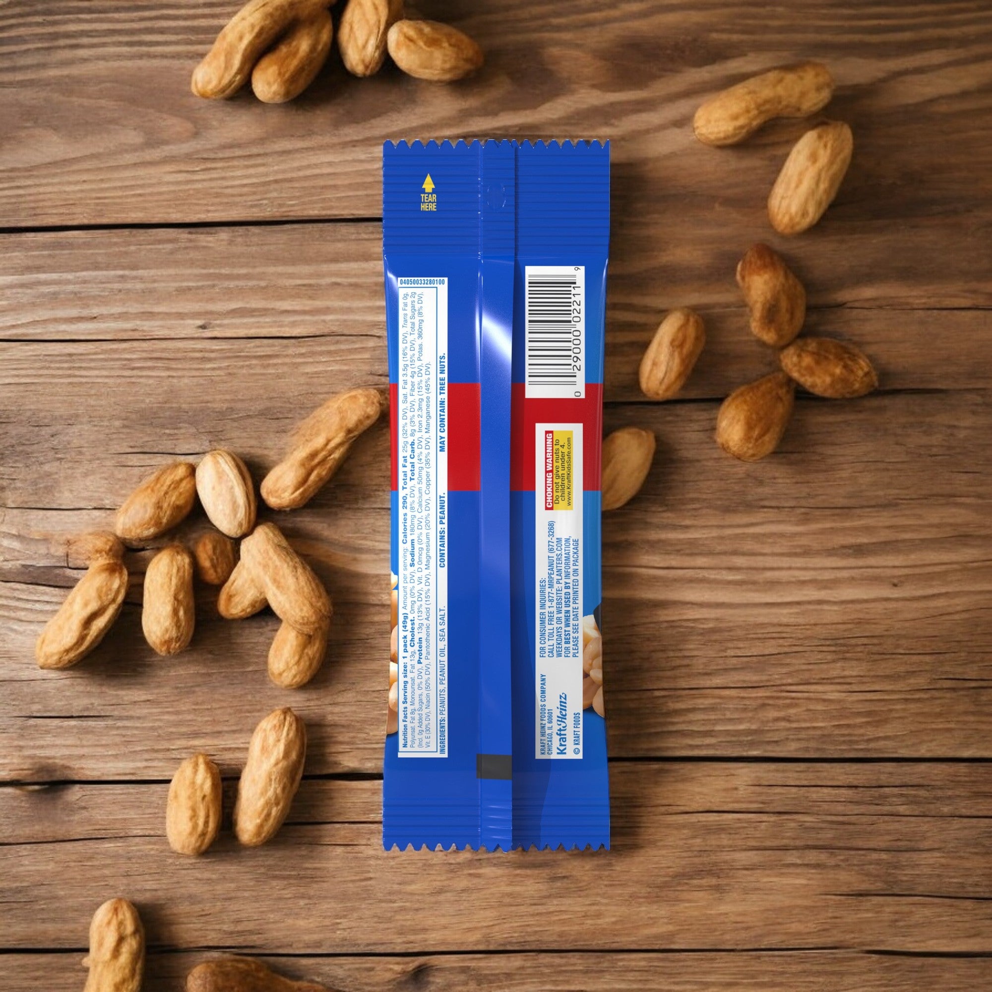 A blue snack bar wrapper with visible nutritional information and a barcode is surrounded by Planters Peanuts from the 5 bags of 1.5 oz each on a wooden surface.