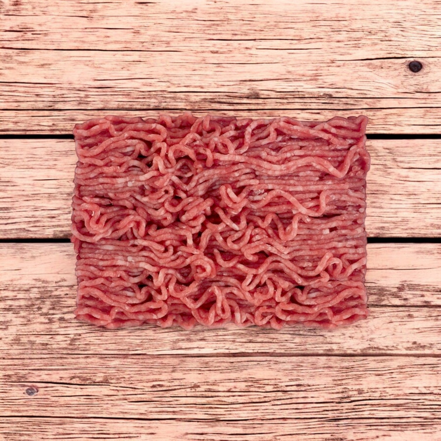 A vacuum-packaged block of Patuxent Farms Halal Ground Lamb 80/20 rests on a wooden surface.