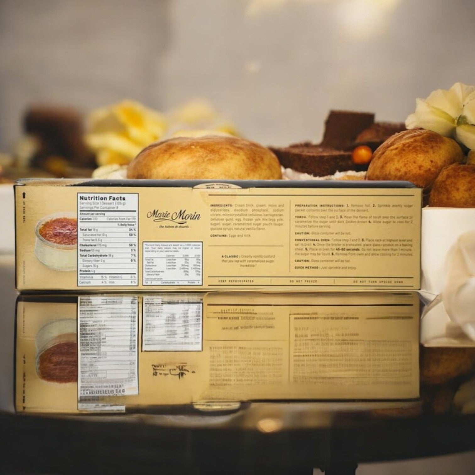 A box of CRÈME BRULEE - MARIE MORIN, measuring 3.7 oz per serving and offered as an 8-count package, rests elegantly on a reflective surface, highlighting its nutritional information on the side. This luxurious dessert beckons indulgence with each bite inspired by French treats.