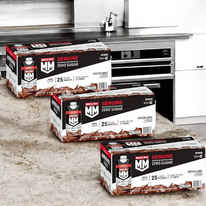 Three cases of Muscle Milk Protein Shakes in chocolate flavor are neatly arranged on a kitchen counter. The packaging emphasizes "Genuine," "Zero Sugar," and "25g Protein" as ideal for muscle recovery. Enjoy each satisfying shake from the trusted brand, Muscle Milk.